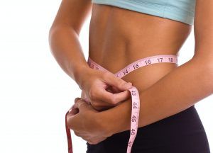 slim woman with measuring tape around stomach