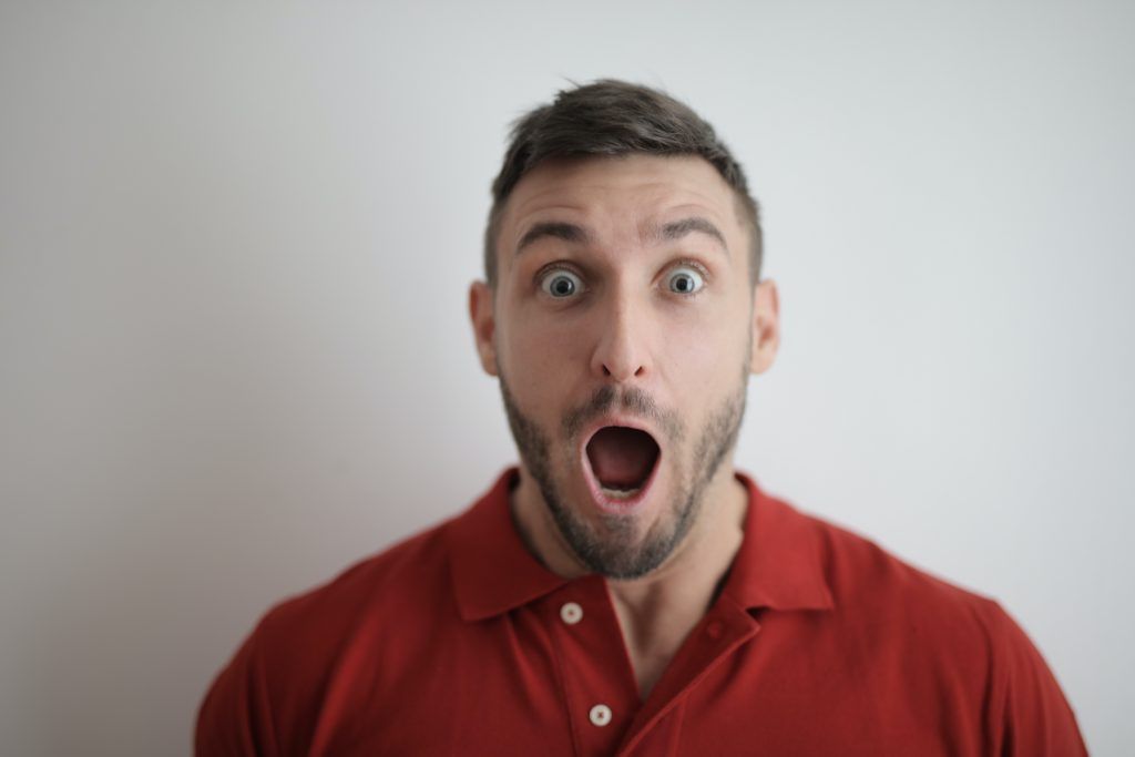 middle aged man in red top looking shocked